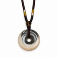 Clear donut pendant with light pet fur around the lower rim and a dark braided cord threaded through its center opening on a white background.
